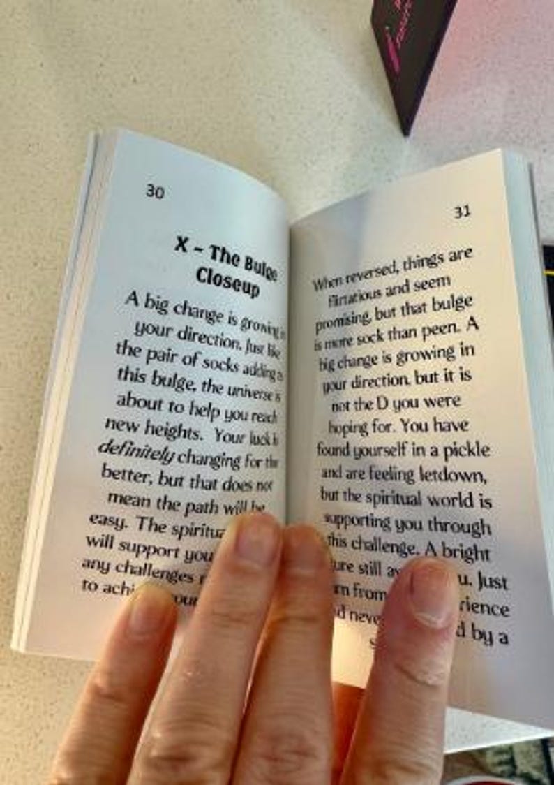 K&ouml;nnte beinhalten: Ein offenes Buch mit Text auf den Seiten, gehalten von einer Hand. Der Text enth&auml;lt den Titel "X - The Bulge Closeup" und andere beschreibende Texte. Das Buch liegt auf einer hellen Oberfl&auml;che.
