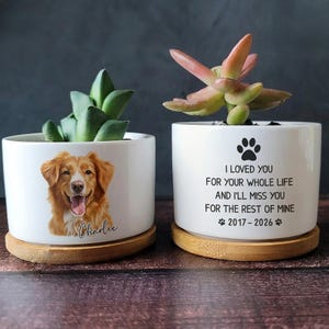 May include: Two white ceramic cylindrical planters on bamboo saucers. One features a portrait of a golden dog with the name Charlie. The other displays a paw print and the text: I LOVED YOU FOR YOUR WHOLE LIFE AND I'LL MISS YOU FOR THE REST OF MINE 2017-2026.