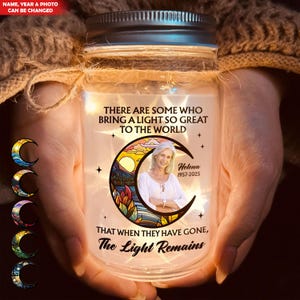 Pode incluir: Um frasco memorial personalizado com tampa prateada, segurado nas mãos. O frasco apresenta uma foto de uma mulher dentro de um design de lua crescente. O texto diz "THERE ARE SOME WHO BRING A LIGHT SO GREAT TO THE WORLD" e "THAT WHEN THEY HAVE GONE, The Light Remains."