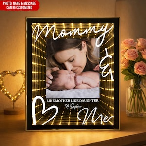 Pode incluir: Uma moldura preta com o texto "Mommy & Me" e "Like Mother Like Daughter Sophia". A foto mostra uma mãe beijando um bebê. A moldura tem um efeito de luz brilhante.
