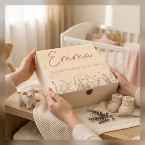 May include: A light-colored wooden keepsake box featuring the name Emma in pink script, the date 26.12.2025, the time 13:41, and birth stats 53 cm and 3100 g. The box lid is decorated with a colorful floral print and has a metal latch.