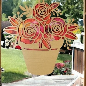 Puede incluir: Un recorte de madera de un ramo de rosas rojas, naranjas y rosas en una maceta. Las rosas son estilizadas y tienen un aspecto vintage. El recorte está pintado con un efecto acuarela.