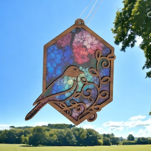 Pu&ograve; includere: Un ornamento in legno a forma di esagono con un uccello ritagliato al centro. L'ornamento &egrave; dipinto con un motivo floreale in tonalit&agrave; di blu, rosa e viola. L'uccello &egrave; rivolto a destra e ha un corpo blu con una testa marrone.