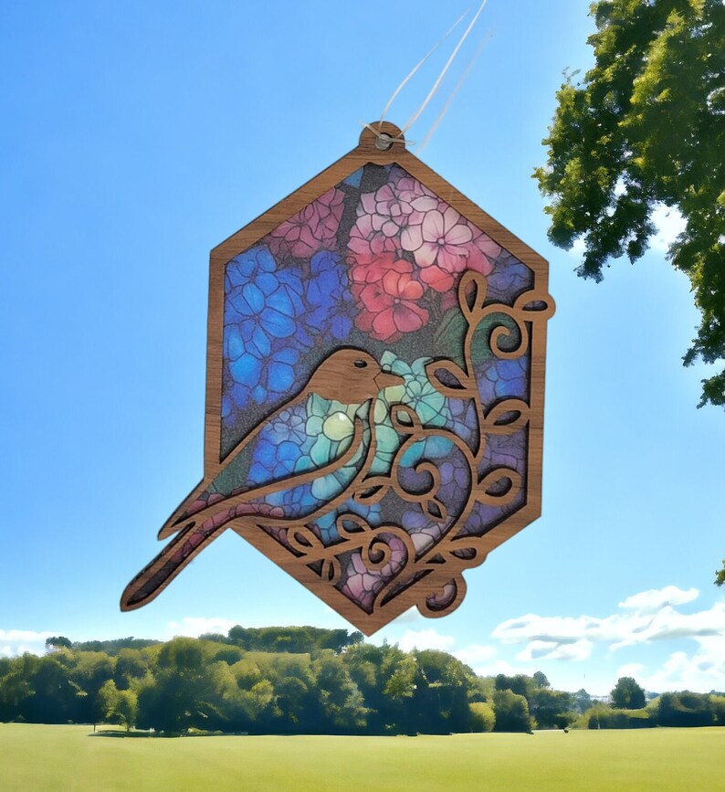 Pu&ograve; includere: Un ornamento in legno a forma di esagono con un uccello ritagliato al centro. L'ornamento &egrave; dipinto con un motivo floreale in tonalit&agrave; di blu, rosa e viola. L'uccello &egrave; rivolto a destra e ha un corpo blu con una testa marrone.