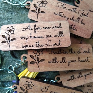 May include: Wooden keychains with floral designs and engraved bible verses. The keychains feature the verses "As for me and my house, we will serve the Lord." and "Trust in the Lord with all your heart."