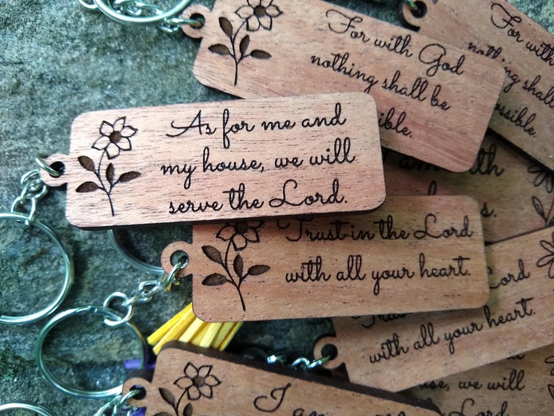 May include: Wooden keychains with floral designs and engraved bible verses. The keychains feature the verses "As for me and my house, we will serve the Lord." and "Trust in the Lord with all your heart."