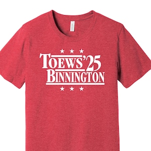 May include: Red heather t-shirt with white text that reads "Toews'25 Binnington" with stars above and below the text.