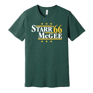May include: A dark green t-shirt with a white graphic that says "STARR'66 McGee" in a vintage political campaign style. The graphic also features five yellow stars above and below the text.