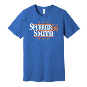 May include: A royal blue t-shirt with a white and orange graphic that says "SPURRIER'66 SMITH" with five stars above and below the text.