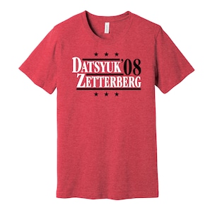 Könnte beinhalten: Rotes melierter T-Shirt mit schwarzem Text, der "Datsyuk'08 Zetterberg" lautet, mit fünf Sternen über und unter dem Text.