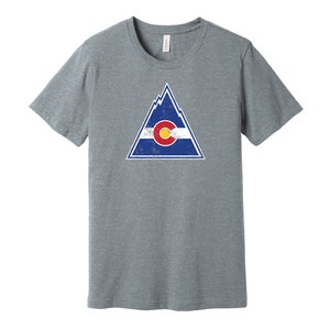 May include: A heather grey t-shirt with a distressed graphic of a mountain range and the Colorado state flag.