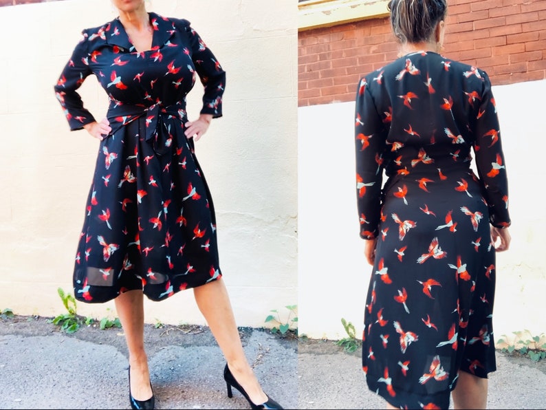 Puede incluir: Un vestido negro de envoltura con estampado de p&aacute;jaros rojos y azules. El vestido tiene manga larga y un lazo en la cintura.