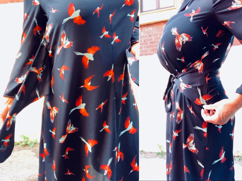Puede incluir: Un vestido negro de envoltura con estampado de p&aacute;jaros rojos y blancos. El vestido tiene mangas largas y un lazo en la cintura.