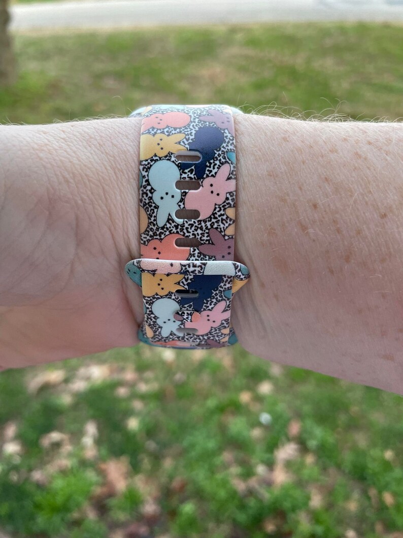 May include: A colourful watch band featuring a pattern of pastel bunnies and a black and white leopard print. The band is made of silicone and has a buckle closure.