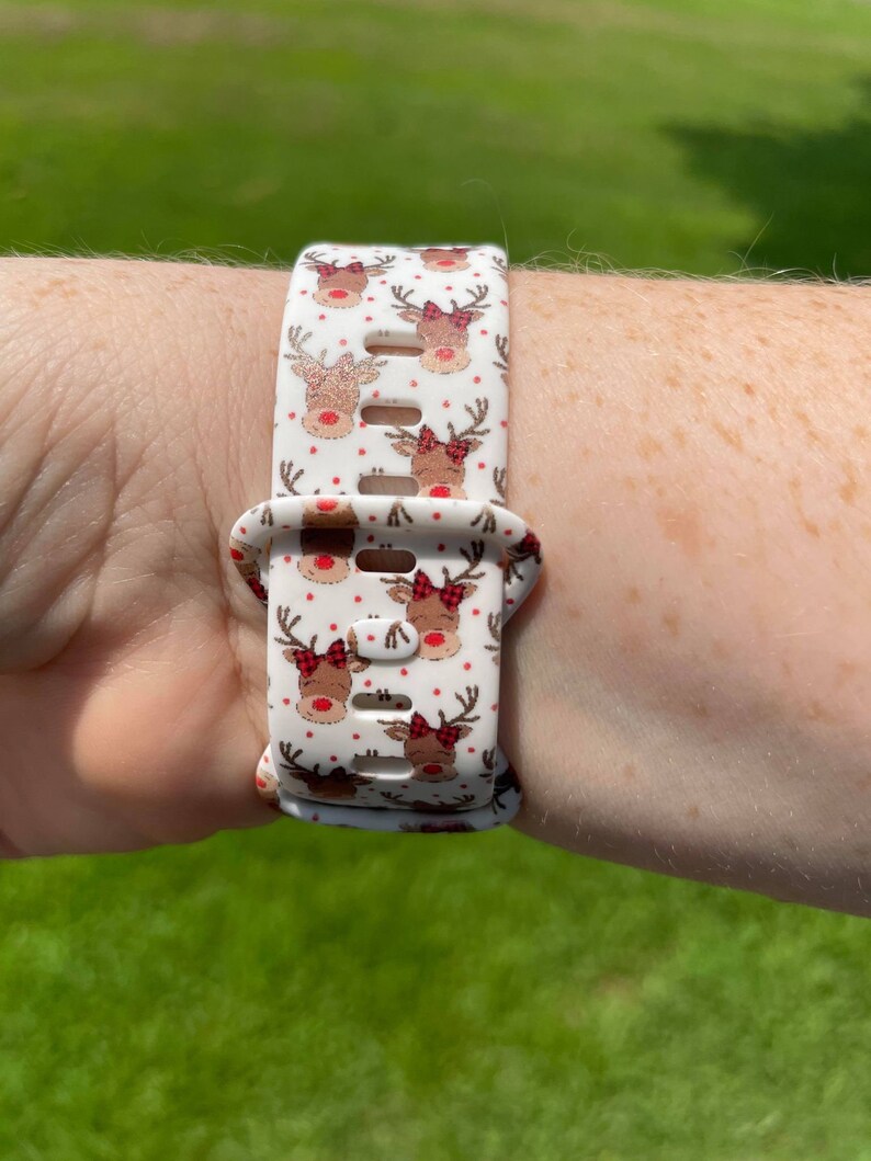 May include: White silicone watch band with a repeating pattern of red-nosed reindeer with red bows.