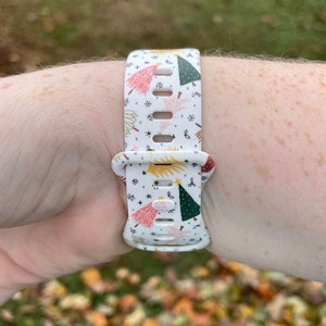 May include: White watch strap with a Christmas tree pattern. The strap has a white background with green, red, pink, and yellow Christmas trees, stars, and other festive designs.