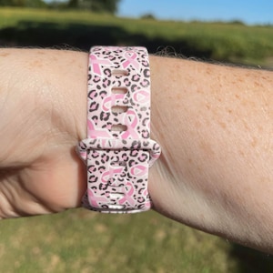 May include: Pink and black leopard print watch band with pink ribbon designs.