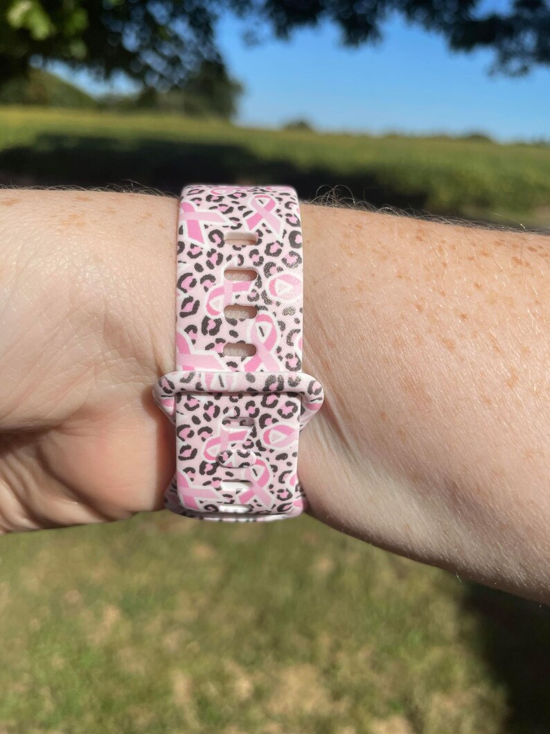 May include: Pink and black leopard print watch band with pink ribbon designs.