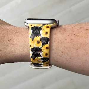 May include: A white Apple Watch band with a pattern of black pugs and yellow sunflowers.