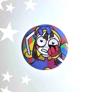 May include: A round button featuring a cartoon character with brown hair, blue eyes, and a red hand covering their face. The character is wearing a colorful costume with a blue, red, and yellow design. The button has a white background.