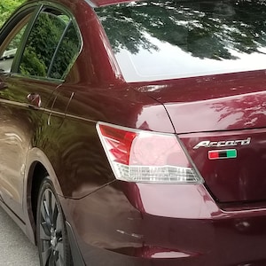 May include: A maroon Honda Accord with a black and green flag sticker on the rear. The car has a number plate that reads "KO".