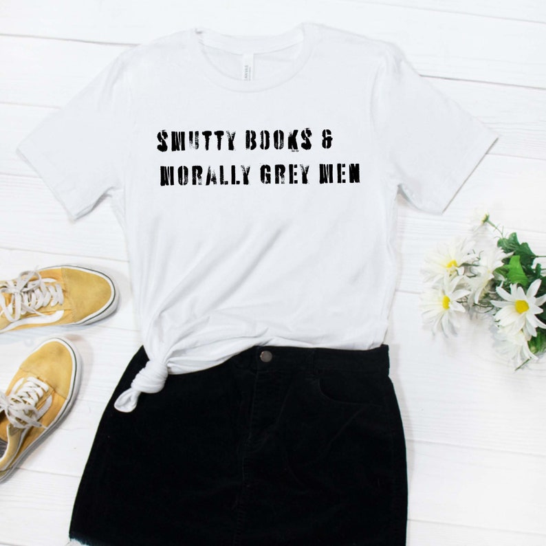 Puede incluir: Camiseta blanca con el texto "SMUTTY BOOKS & MORALLY GREY MEN" impreso en negro.