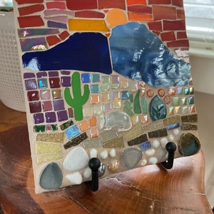 Colorful handmade desert sunset mosaic using red, orange, blue tiles with armadillo and cactus