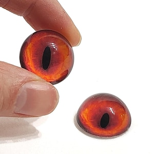 May include: Two red and black glass eyes with a black pupil. The eyes are round and have a glossy finish.
