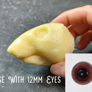 May include: A light yellow, bird-shaped craft item with a textured surface. The text "USE WITH 12MM EYES" is visible. A close-up of a brown eye is in the lower right corner.