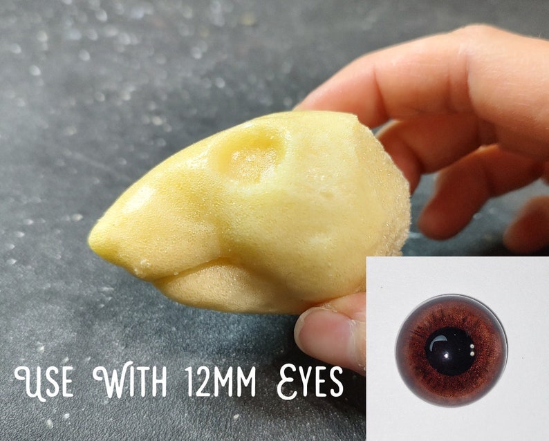 May include: A light yellow, bird-shaped craft item with a textured surface. The text "USE WITH 12MM EYES" is visible. A close-up of a brown eye is in the lower right corner.