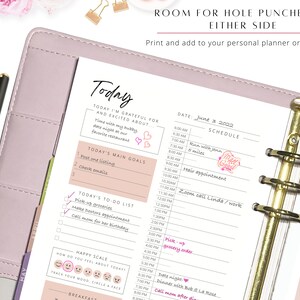 May include: A pink daily planner with a gold binder and a page that says "Today" with a to-do list, main goals, and a happy scale. The date is June 3, 2022.