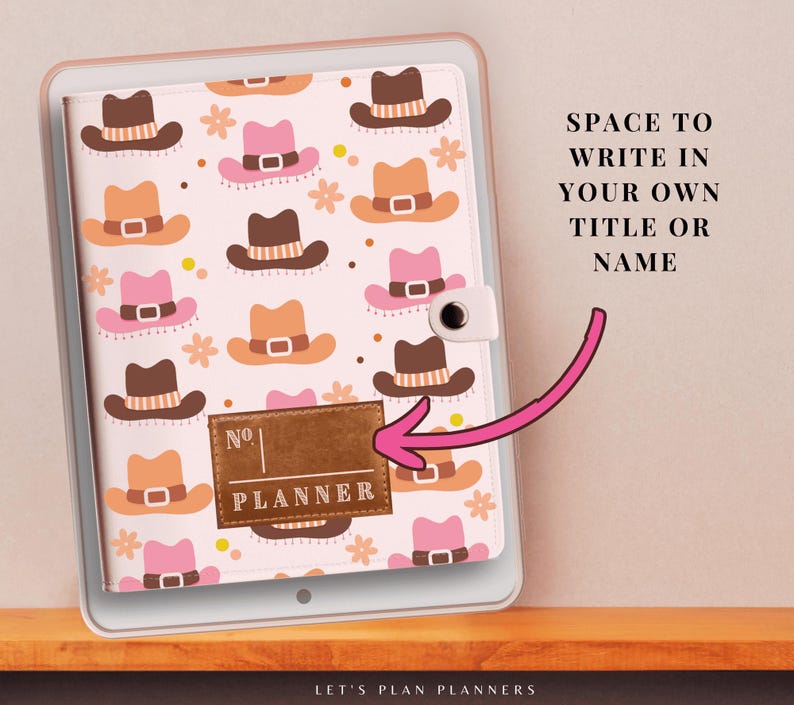 May include: A white planner with a brown leather cover and a pink and brown cowboy hat pattern. The cover has a brown leather label with the text "No. PLANNER" on it. The planner has a space to write in your own title or name.