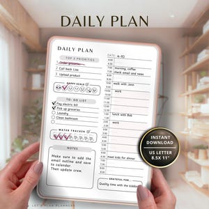 May include: A white daily planner with a pink border is held by hands. The planner includes sections for top priorities, a to-do list, a water tracker, and a schedule. The text "DAILY PLAN" is at the top. The planner is US Letter size, 8.5 x 11 inches.