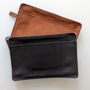May include: Two leather laptop sleeves, one brown and one black. Both sleeves have a zipper closure.
