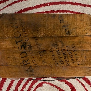 Op de afbeelding: Een bruine houten vaten deksel met zichtbare houtnerf en zwarte gestempelde tekst met de tekst ARDSTON, URBANA, OHIO, C-73-6, 125 PROOF, NESIC, 145373 en 130 NO. Het vat is opgebouwd uit verschillende horizontale houten planken.