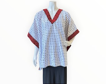 May include: White, short-sleeved tunic with a black dotted pattern. The tunic has a V-neck and trim in a dark red color. The sleeves and neckline are accented with a detailed red border. The tunic is displayed on a mannequin.