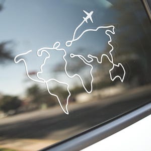 May include: A white decal of a world map with a plane taking off, applied to a car window. The design is a continuous line, depicting continents and an airplane, suggesting travel and adventure.