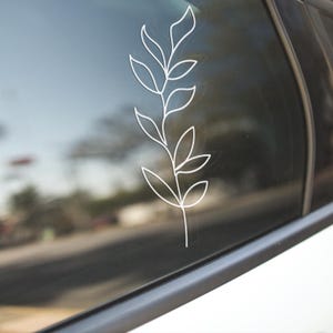 May include: A white outline of a leafy branch on a car window.