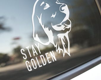 May include: White vinyl decal of a golden retriever dog with the text "STAY GOLDEN" on a car window.
