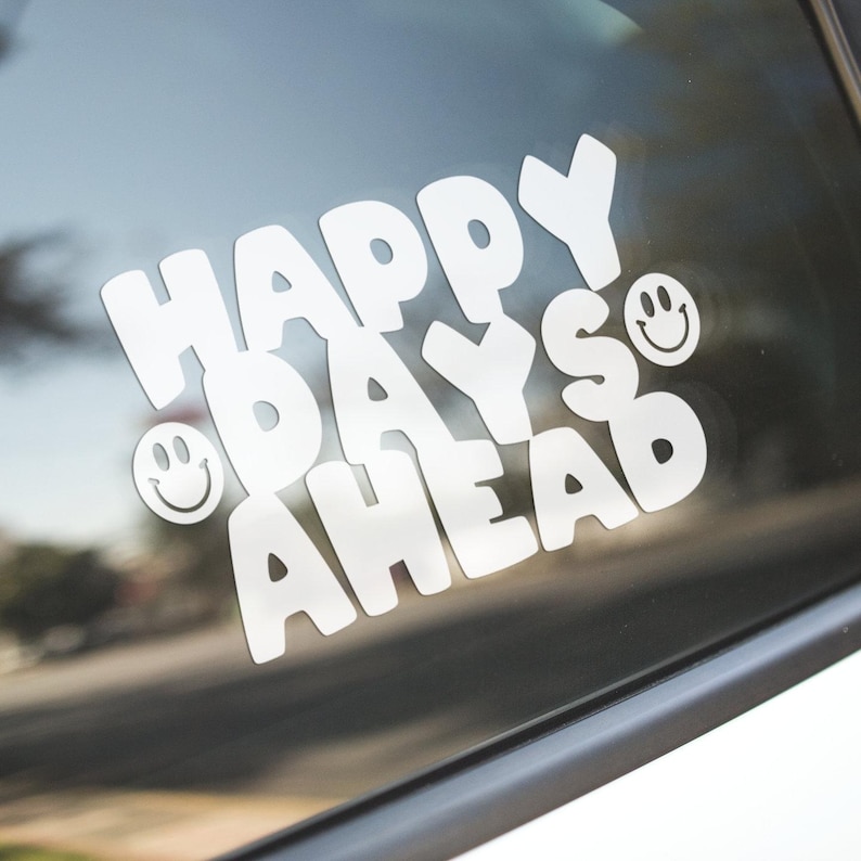 May include: White vinyl sticker with the text "Happy Days Ahead" in a retro font with two smiley faces.