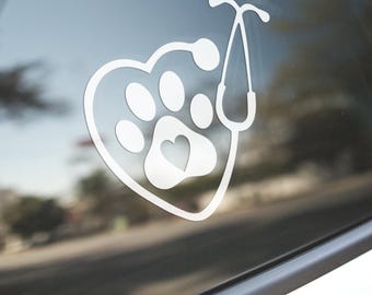 May include: White vinyl decal of a paw print inside a heart shape with a stethoscope on top. The paw print has a small heart inside.