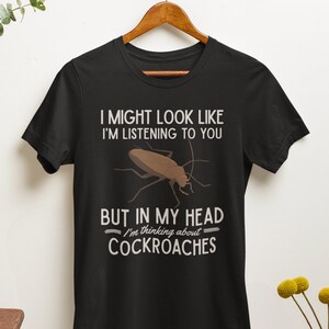 May include: Black t-shirt with a white graphic of a cockroach and the text "I might look like I'm listening to you, but in my head I'm thinking about cockroaches."