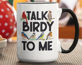 May include: White ceramic mug with a black handle. The mug has a colorful illustration of birds and the text "Talk Birdy To Me".