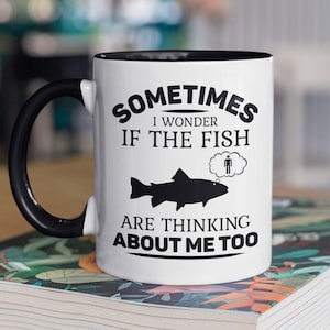 May include: White ceramic mug with a black handle and black rim. The mug has a black graphic that says "Sometimes I wonder if the fish are thinking about me too." The graphic includes a silhouette of a fish and a thought bubble with a stick figure inside.