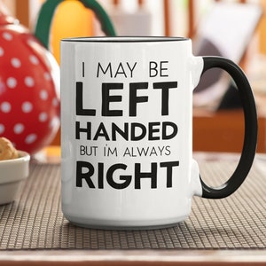 May include: White ceramic mug with a black handle and black text that reads "I may be left handed but I'm always right".