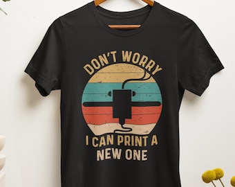 Könnte beinhalten: Schwarzes T-Shirt mit einer Grafik im Vintage-Stil eines 3D-Druckers. Die Grafik hat einen roten, orangefarbenen und gelben Sonnenuntergangs-Hintergrund mit dem Text "Keine Sorge, ich kann einen neuen drucken".