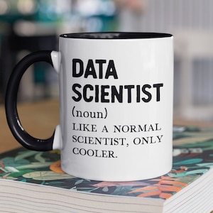 Peut inclure: Une tasse blanche avec un bord et une poignée noirs. La tasse porte une inscription noire qui dit "DATA SCIENTIST (nom) COMME UN SCIENTIFIQUE NORMAL, MAIS PLUS COOL."
