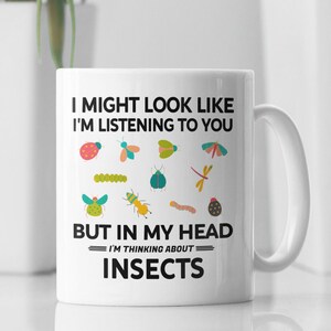 May include: White ceramic mug with a black and white graphic that says "I might look like I'm listening to you but in my head I'm thinking about insects". The graphic includes a variety of colorful insects.
