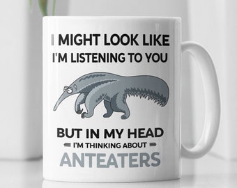 May include: White ceramic mug featuring a black and grey illustration of an anteater. The mug has the text "I might look like I'm listening to you, but in my head = I'm thinking about = anteaters".