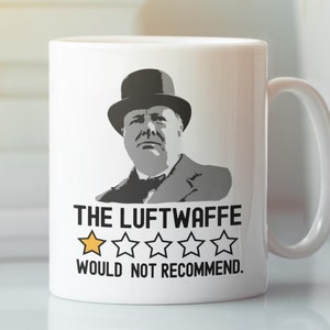 Op de afbeelding: Witte keramische mok met een zwart-wit portret van een man met een bolhoed. De tekst "THE LUFTWAFFE WOULD NOT RECOMMEND" staat eronder, samen met een beoordeling van één ster. De mok heeft een wit oor.
